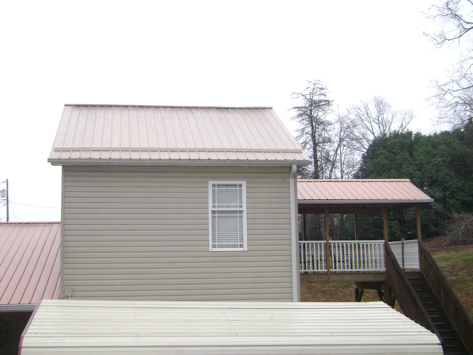 Tan metal roofs on a two story addition and attached porch in Clayton